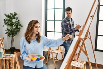 Two hispanic students painting at art school. Man looking partner draw.