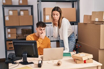 Young couple working at small business ecommerce covering mouth with hand, shocked and afraid for mistake. surprised expression