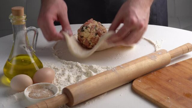 Chef puts meat filling in dough for Ossetian pie and kneading dought. Caucasian traditional food