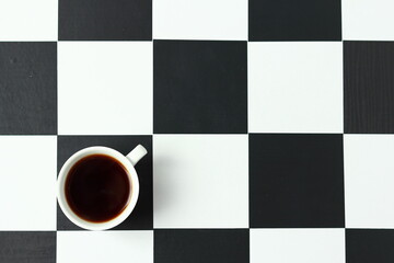 A cup of coffee on a chessboard.