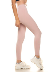 Side view of a female legs in sport pink tights and sneakers on white background