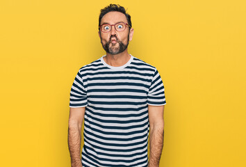 Middle age man wearing casual clothes and glasses making fish face with lips, crazy and comical gesture. funny expression.