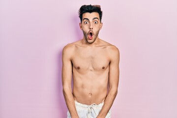 Fototapeta premium Young hispanic man wearing swimwear shirtless afraid and shocked with surprise expression, fear and excited face.
