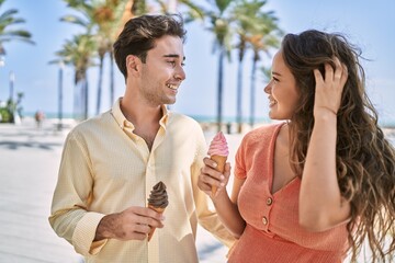 Man and woman couple eating ice cream and hugging each other at seaside