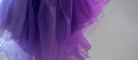 Сlose-up of violet blue chiffon dress curiously bending under the hands of a girl in the studio....