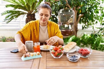 Young hispanic girl having breakfast sitting on the table at terrace.