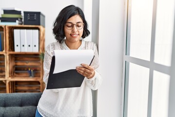 Young latin woman having psychology session writing on clipboard at psychology center