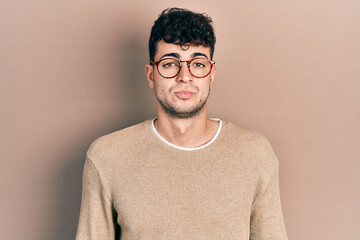 Young hispanic man wearing casual clothes and glasses looking sleepy and tired, exhausted for fatigue and hangover, lazy eyes in the morning.