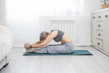 adult woman in sportswear is engaged in stretching at home