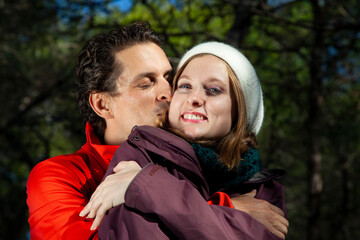 Fototapeta premium Hombre vestido con ropa invernal besando y abrazando a su pareja. Sol y frío. 