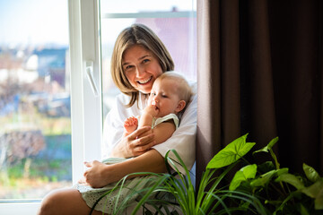 Portrait beautiful young european mother holding and hugging her newborn baby in living room. Health care and Happiness love woman lifestyle, mother's day concept