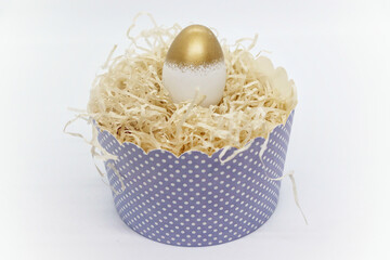 Golden Easter egg lies in a paper baking dish on the street