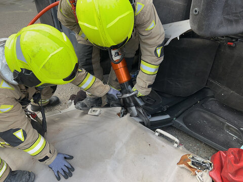 The Rescue Team Of Firefighters At The Scene Of The Traffic Accident Of The Car Accident. Firefighters Grab Their Tools, Gear And Equipment And Rush To Help Injured And Trapped People