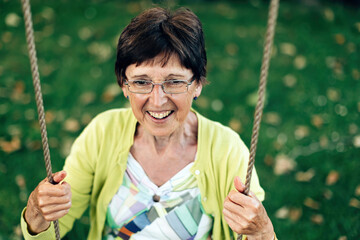 happy elderly woman on swing