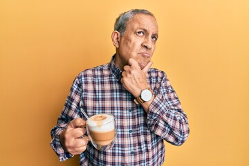 Handsome senior man with grey hair drinking a cup coffee thinking worried about a question,...