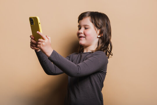 Girl Shows Her Fallen Tooth Socket On Mobile Phone On Beige Background