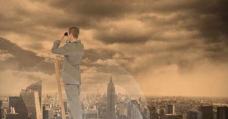 Composition of caucasian businessman on ladder looking through binoculars over cityscape