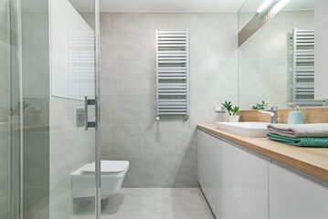 Jasna łazienka z dużym lustrem i umywlką, pojemnymi szafkami oraz kabiną prysznicową - obrazy, fototapety, plakaty