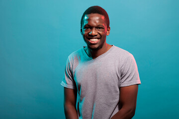 Fototapeta premium Portrait of happy adult smiling in front of camera, showing positive and joyful facial expressions. Casual person enjoying carefree lifestyle with cheerful emotion over background.