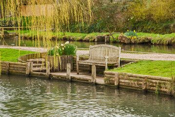 Wooden bench in rest place by river bank closeup