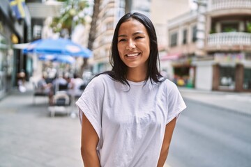 Young latin girl smiling happy standing at the city.