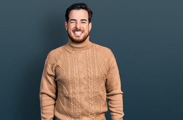 Young hispanic man wearing casual clothes winking looking at the camera with sexy expression, cheerful and happy face.