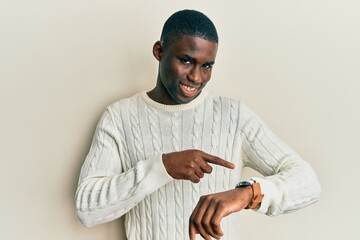 Young african american man wearing casual clothes in hurry pointing to watch time, impatience,...