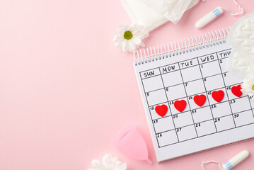 Top view photo of red heart marks on the calendar camomile buds menstrual cup hygienic pads and...