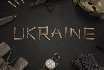 Fototapeta na wymiar Ukraine war concept. Ukraine text written with bullets from an automatic rifle and surrounded by military equipment