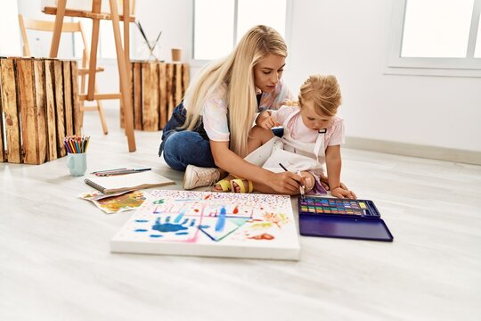 Mother and daughter drawing sitting on floor at art studio