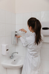 The doctor in white uniform disinfects his hands. Surgeon washing hands hospital concept. The nurse...