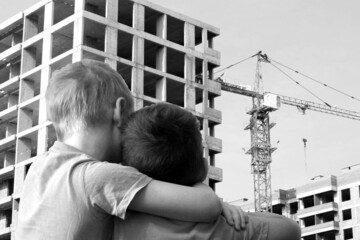 Two boys look at a building under construction, housing for children