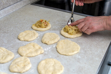 hands of a female cook put the stuffing in the pies.