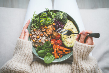 Woman holding plate with tasty vegan or vegetarian food. Healthy vegan meal. Vegan buddha bowl with...