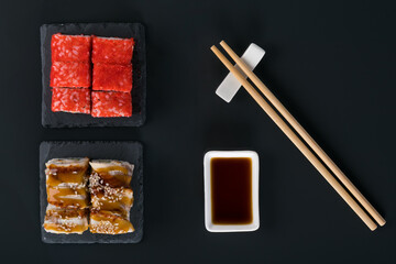 set of rolls with eel and caviar on the table next to soy sauce and chopsticks, top view