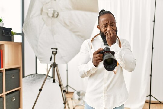 African american photographer man working at photography studio looking stressed and nervous with hands on mouth biting nails. anxiety problem.