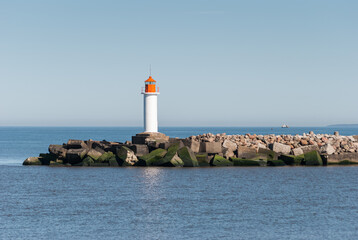 Mole with lighthouse and concrete blocks in sunny day, Ventspils, Latvia.