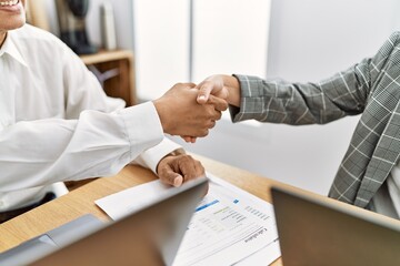 Middle age man and woman business workers high five raised up hands working at office