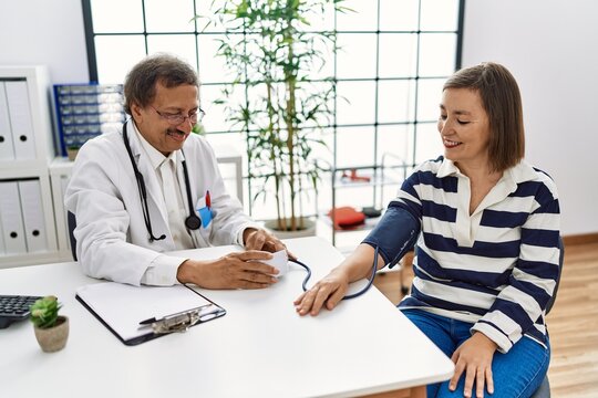 Middle age man and woman wearing doctor uniform having medical consultation auscultating using stethoscope at clinic