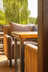 Summer cafe terrace with chairs and wooden table on sunny day. Empty seats at the balcony of street restaurant.