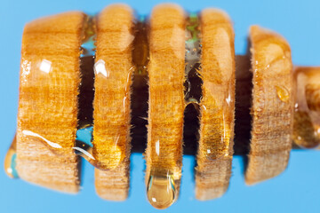 Wooden honey dipper with golden honey and air bubbles. Extreme close up, macro
