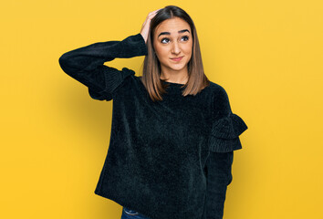 Beautiful brunette woman wearing elegant sweater confuse and wonder about question. uncertain with doubt, thinking with hand on head. pensive concept.