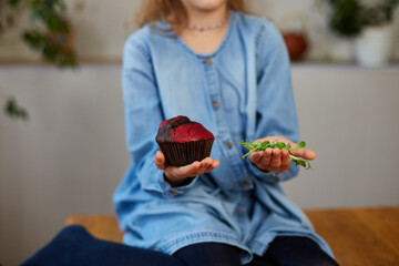 Little girl comparing food, choosing microgreen against sweet cake, Healthy dieting habit