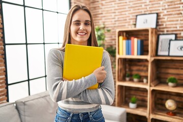 Young woman holding notebook winking looking at the camera with sexy expression, cheerful and happy...