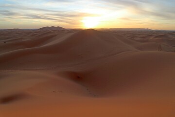 Sun at horizon in the sand dunes of Erg Chebbi desert during golden hour at sunset in Morcco