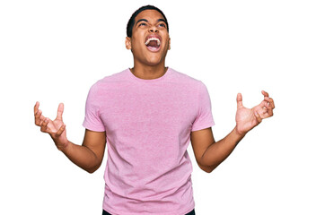 Young handsome hispanic man wearing casual pink t shirt crazy and mad shouting and yelling with aggressive expression and arms raised. frustration concept.