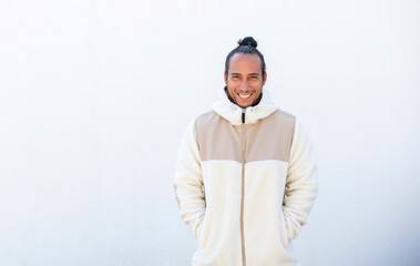 Happy man in winter jacket with hands in pocket over white background