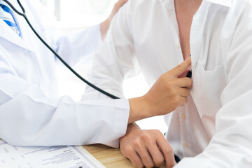 Visiting a doctor concept A patient sitting still and being examined on his chest by a doctor.