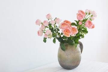 bouquet of peony roses in ceramic jug on white background