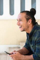Fototapeta premium Happy man using mobile phone while sitting outdoors on staircase